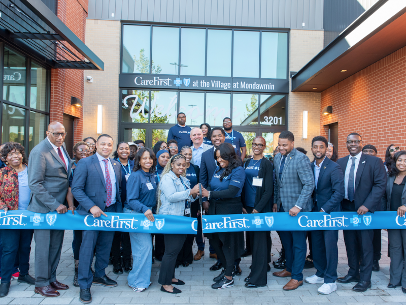 group of people at ribbon cutting ceremony in front of building with glass front